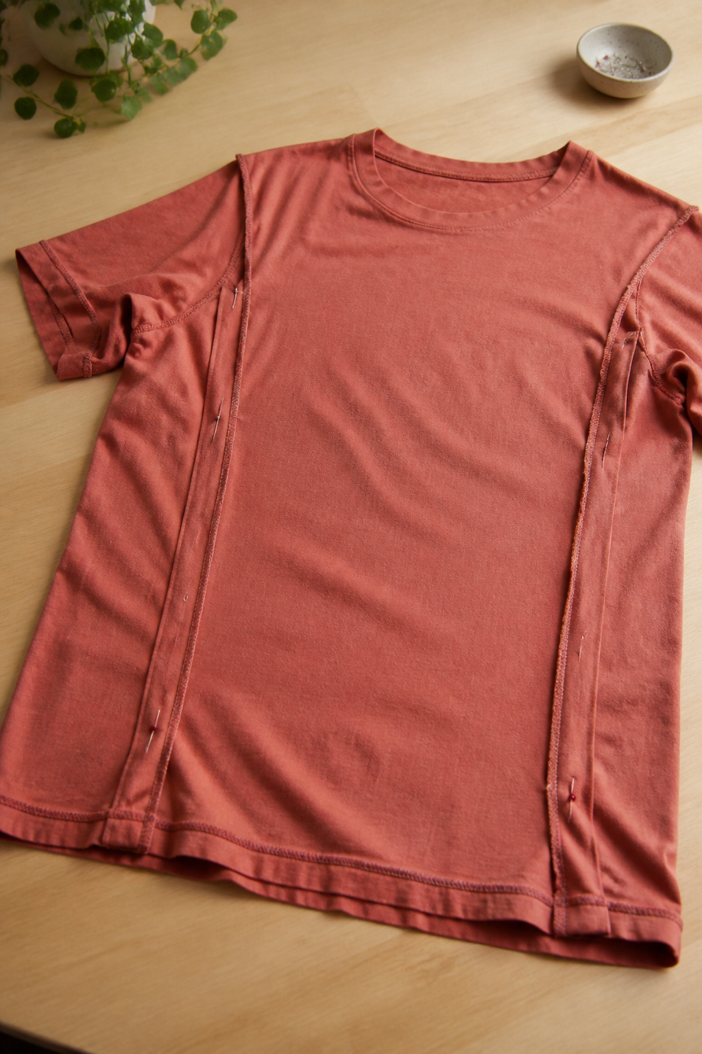 Tee-shirt retourné sur l'envers et posé à plat, une nouvelle ligne de couture marquée à la craie et maintenue par des épingles le long du côté